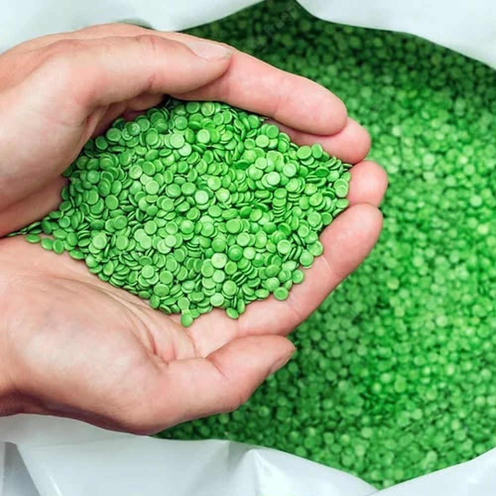 Cupped hands holding green coated seed pellets